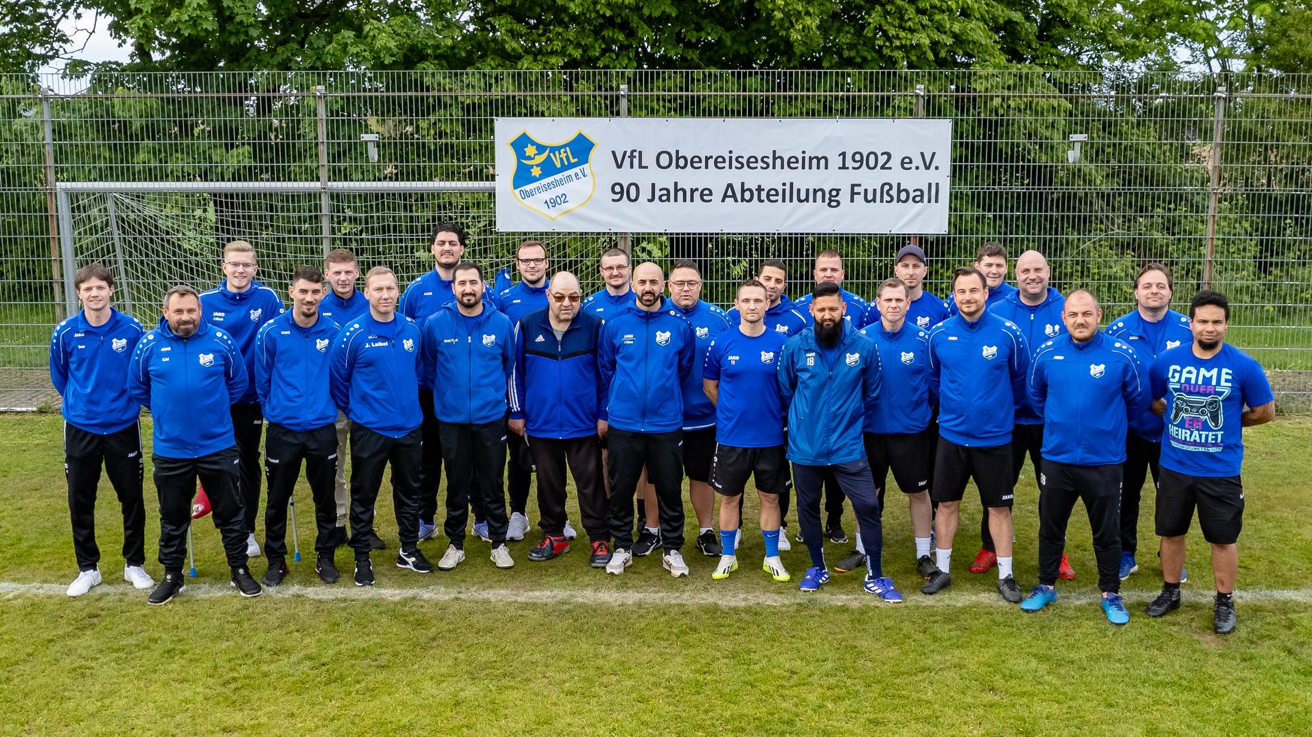 Gruppenfoto der Fu&szlig;ballmannschaft des VfL Obereisesheim 1902 e.V. vor einem Banner zum 90-j&auml;hrigen Jubil&auml;um.