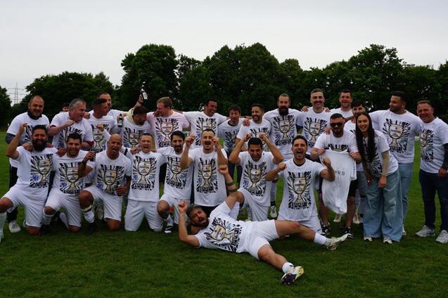 Gruppe von Fu&szlig;ballspielern in wei&szlig;en T-Shirts, posierend auf einem gr&uuml;nen Rasenfeld, feiern zusammen.